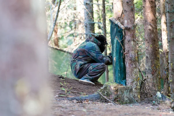 Paintball Player in Camouflage Clothing Hiding during Game