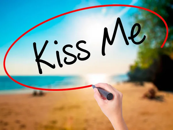 Women Hand writing Kiss Me with black marker on visual screen. Isolated on beach. Business, technology, internet concept. Stock Photo