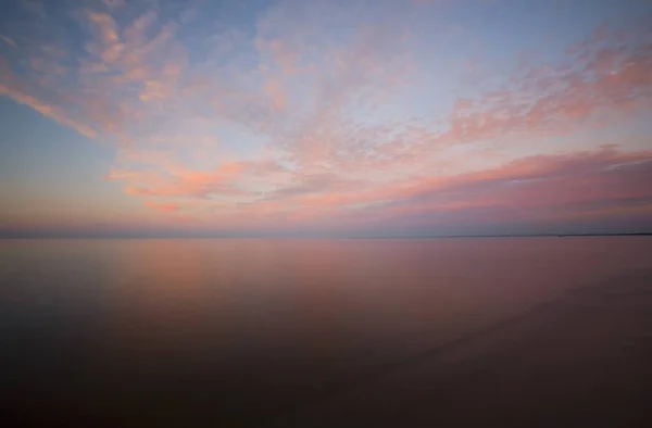Sunset sky with clouds over the smooth water of Lake Superior.