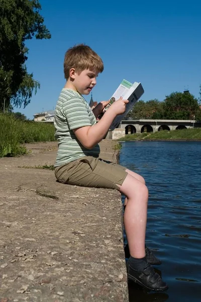 Niño Pequeño Lee Gran Libro Con Río Fondo — Foto de Stock