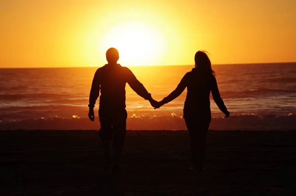 日没の背景とビーチでカップル — ストック写真