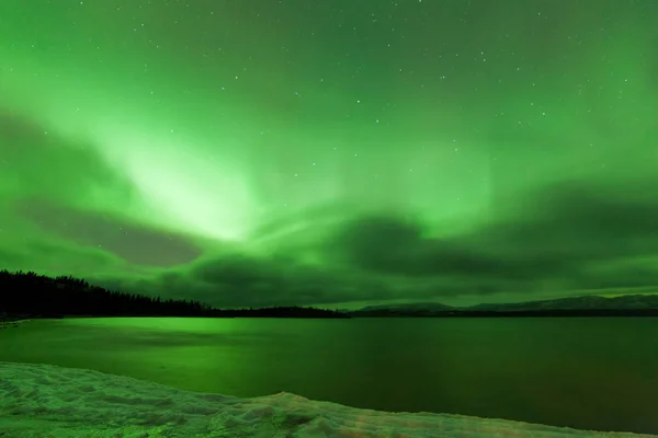 ラバージュ湖 ユーコン準州 カナダの曇り夜空の冬のシーンにオーロラボレアリスやオーロラの緑の輝くショー — ストック写真