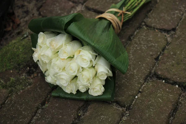 White sympathy roses in a small bouquet on the pavement