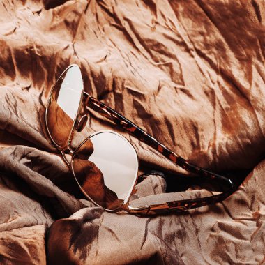 kahverengi parlak kumaş üzerine güneş gözlüğü