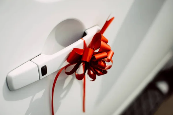 white car door handle decorated with red bow