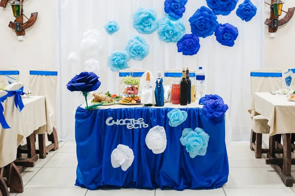 the table of the bride and groom with blue decor and the inscription in Russian, 