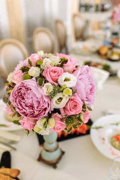 bouquet of peonies and roses in a vase on a served table