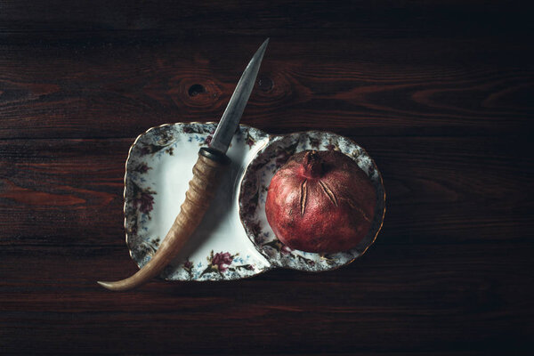 pomegranate and knife on a dark wooden background