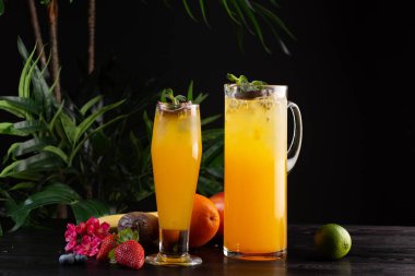 Mango limonata - tutku meyve bir sürahi ve bardak ve koyu ahşap arka plan üzerinde meyve