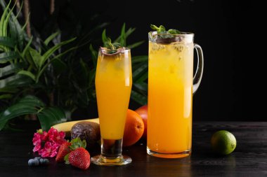 Mango limonata - tutku meyve bir sürahi ve bardak ve koyu ahşap arka plan üzerinde meyve