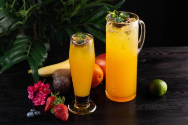 Mango limonata - tutku meyve bir sürahi ve bardak ve koyu ahşap arka plan üzerinde meyve