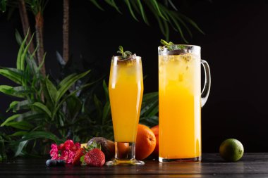 Mango limonata - tutku meyve bir sürahi ve bardak ve koyu ahşap arka plan üzerinde meyve