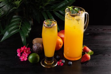 Mango limonata - tutku meyve bir sürahi ve bardak ve koyu ahşap arka plan üzerinde meyve