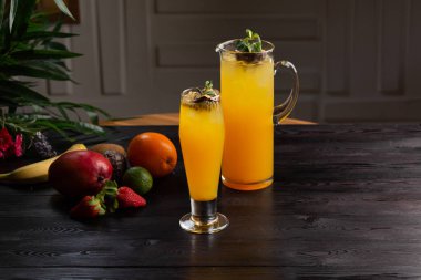 Mango limonata - tutku meyve bir sürahi ve bardak ve koyu ahşap arka plan üzerinde meyve