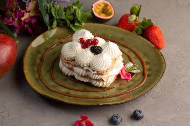 Kek krem şanti ve yeşil bir plaka üzerinde çilek