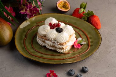 Kek krem şanti ve yeşil bir plaka üzerinde çilek