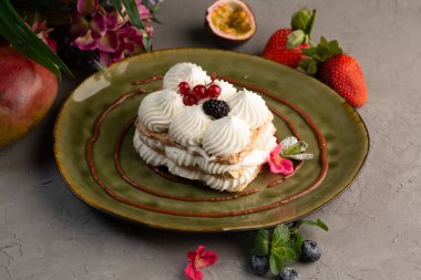 Kek krem şanti ve yeşil bir plaka üzerinde çilek