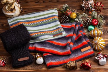 Örme çizgili çizgili eşarp, siyah örme kollu ve Noel oyuncakları ahşap arka planda