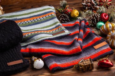 Örme çizgili çizgili eşarp, siyah örme kollu ve Noel oyuncakları ahşap arka planda