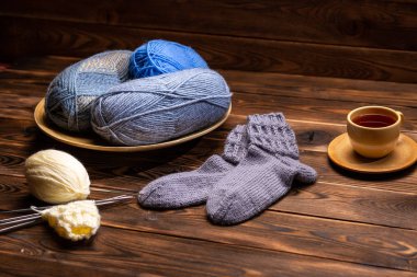 gri Örme Çorap, örme iplikler ve ahşap bir arka planda bir bardak çay bir fincan