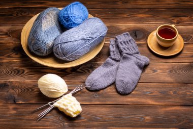 gri Örme Çorap, örme iplikler ve ahşap bir arka planda bir bardak çay bir fincan