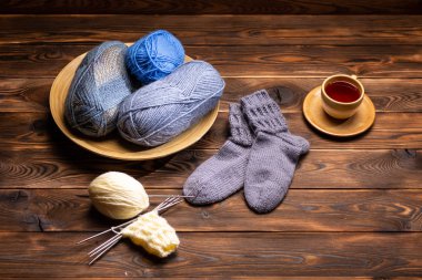 gri Örme Çorap, örme iplikler ve ahşap bir arka planda bir bardak çay bir fincan