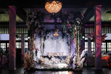 çiçekler ve tavana asılı şık bir avize ile dekore edilmiş bir düğün salonu