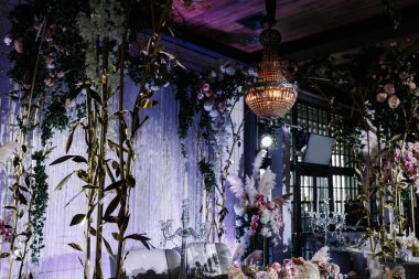 çiçekler ve tavana asılı şık bir avize ile dekore edilmiş bir düğün salonu