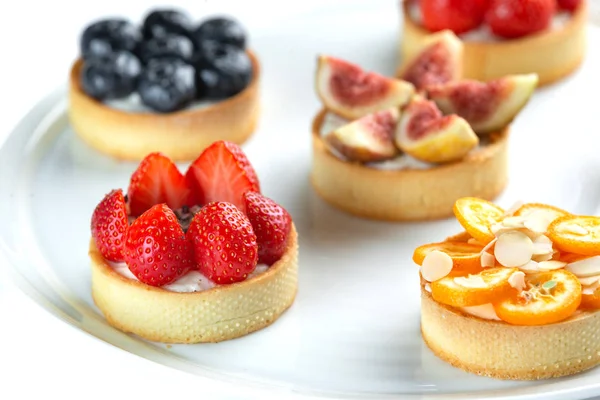 izole beyaz arka planda bir plaka meyve ve çilek ile Tartlets