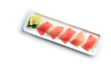 izole beyaz arka planda dikdörtgen bir plaka üzerinde limon ve otlar ile kırmızı balık parçaları