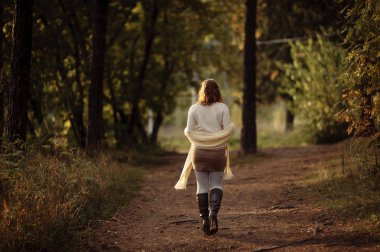 sonbahar ormanında ağaç gövdeleri bir arka plan karşı parlak giysiler içinde kızıl saçlı kız
