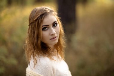 güneşli bir günde sonbahar orman bir arka plan üzerinde parlak giysiler içinde kızıl saçlı kız