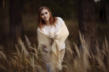 güneşli bir günde sonbahar orman ve sarı kulakları bir arka plan üzerinde parlak giysiler içinde kızıl saçlı kız