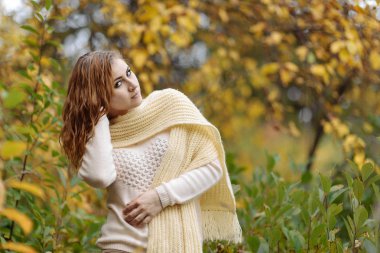 güneşli bir günde sonbahar orman bir arka plan üzerinde parlak giysiler içinde kızıl saçlı kız