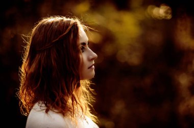 güneşli bir günde sonbahar orman bir arka plan üzerinde parlak giysiler içinde kızıl saçlı kız