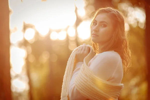 red-haired girl in light clothes against the backdrop of the autumn forest against sunlight