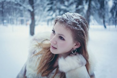 kış ormanının arka planına karşı saçları akan saç ve kar ile parlak bir kürk ceket kız
