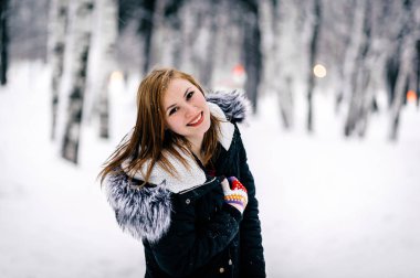 kış ormanı ortasında kürk kapüşonlu siyah ceketgüzel bir kız portresi