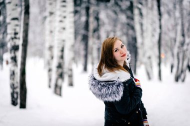 kış ormanı ortasında kürk kapüşonlu siyah ceketgüzel bir kız portresi