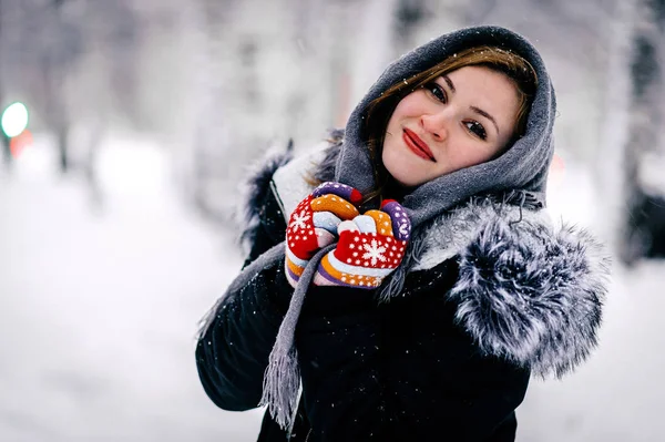 Portrait of a girl in grey headscarf, black jacket and colored gloves against the backdrop of the winter forest — Stock Photo, Image