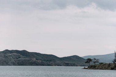 Kıyıdan Chirkei rezervuarına açılan manzara. Bulutlu gökyüzünün arka planında dağlar. Sulak Kanyonu, Dağıstan