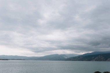Kıyıdan Chirkei rezervuarına açılan manzara. Bulutlu gökyüzünün arka planında dağlar. Sulak Kanyonu, Dağıstan