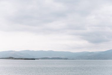 Kıyıdan Chirkei rezervuarına açılan manzara. Bulutlu gökyüzünün arka planında dağlar. Sulak Kanyonu, Dağıstan