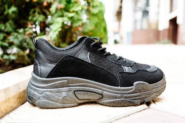 Black sneakers on thick black soles against the background of paving slabs — Stock Photo, Image