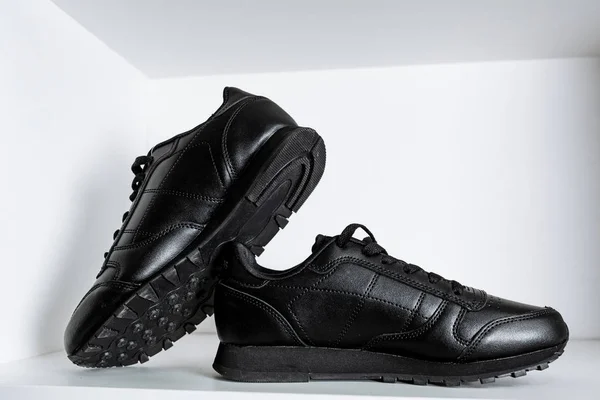Een paar zwarte trendy sneakers op de witte plank in de winkel — Stockfoto
