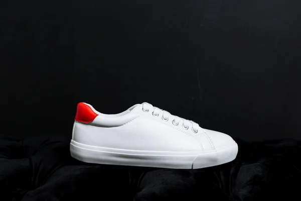 Білі кросівки з червоною спиною на темному фоні — стокове фото