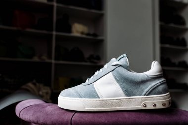 Dükkanın arka planında beyaz aksanlı beyaz taban üzerinde mavi süet spor ayakkabı bir çift