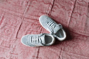 Pembe arka planda beyaz aksanlı beyaz taban üzerinde mavi süet spor ayakkabı bir çift