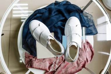 Cam bir masanın topuğunda yapay elmaslardan yapılmış bir yıldız olan beyaz spor ayakkabıları.