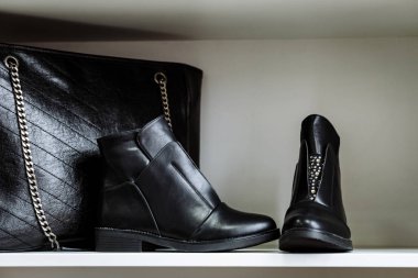 siyah deri ayakkabı rhinestones ve mağazada beyaz bir rafta bir zincir üzerinde siyah deri çanta ile dekore